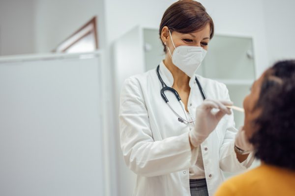 Doctor doing medical examination of a female patient's throat.
