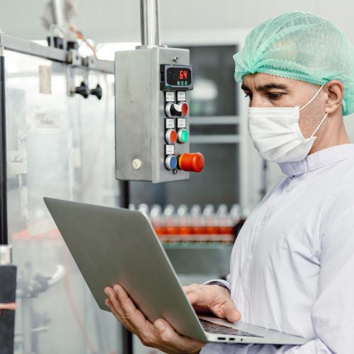 engineer working with laptop in food factory machine production inspector with hygiene clothes.